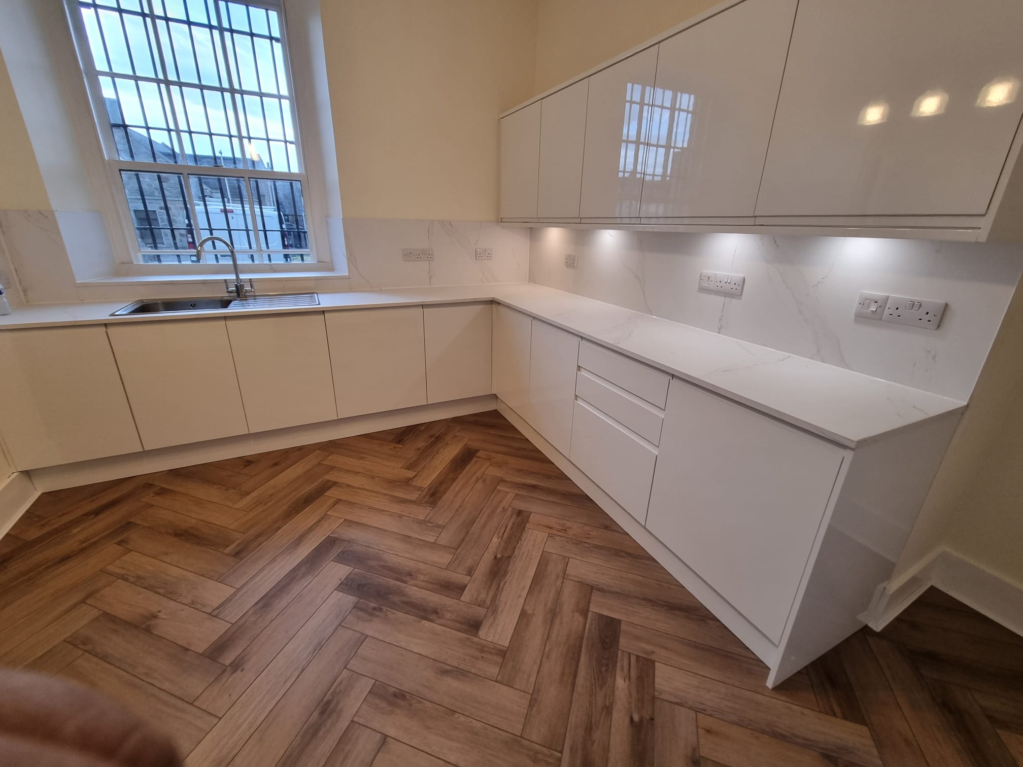 A modern kitchen bathed in natural light from a large window on the left wall