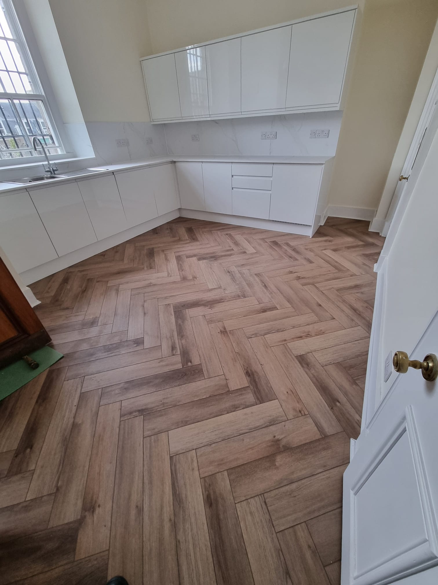 A serene indoor setting, bathed in soft light that accentuates the warm tones of the wooden floor and the pristine white walls