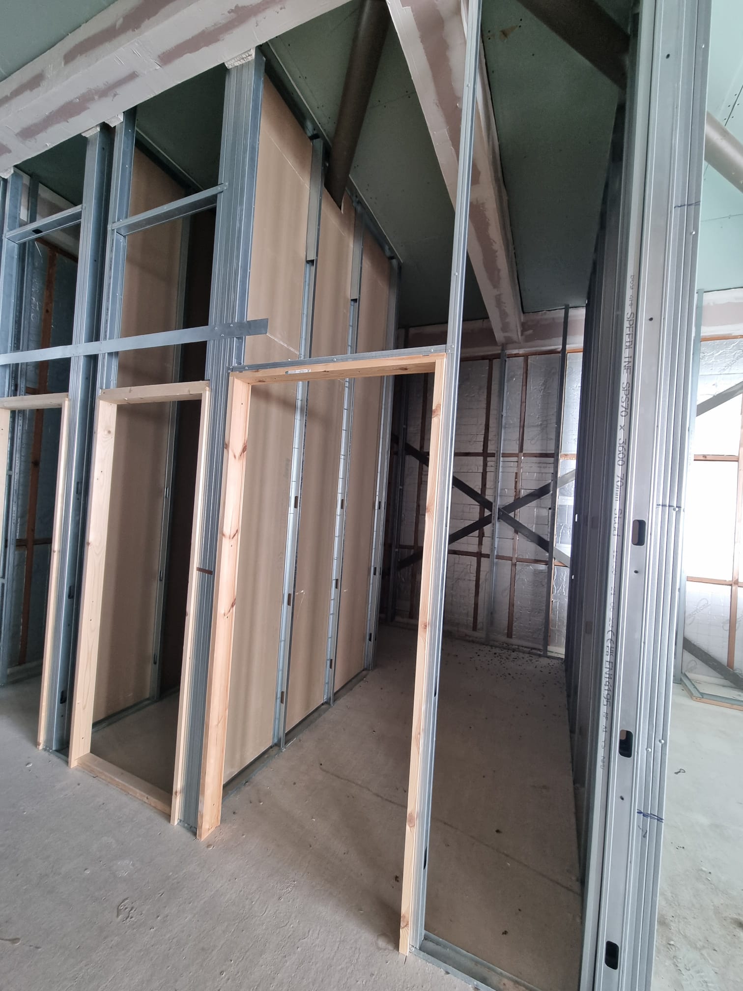 A room under construction, bathed in natural light filtering through an open window on the right wall